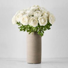 a vase with white roses in it on a table