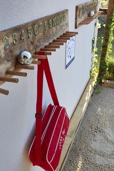 a red duffle bag hanging on the side of a wall with numbers and hooks