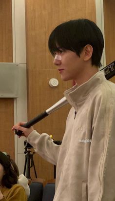 a young man holding a baseball bat in his hand while standing next to a woman