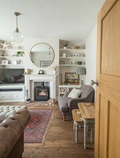 a living room filled with furniture and a fire place under a mirror on the wall