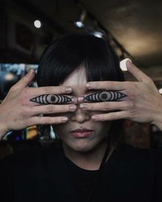 a woman holding her hands up to her eyes with two circles on the top of their fingers