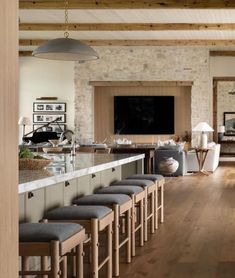 an open kitchen and living room area with bar stools in front of the counter