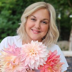 a woman holding three pink and white flowers