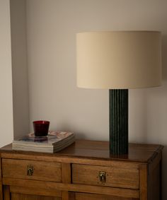 a lamp on top of a dresser next to a book