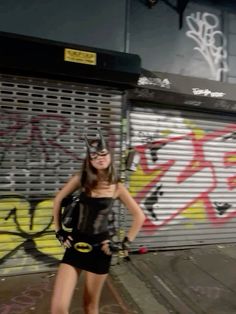 a woman standing in front of a graffiti covered wall with her hands on her hips