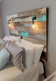 a bed with white pillows and wooden headboard made from pallet wood, sitting in a bedroom next to a window