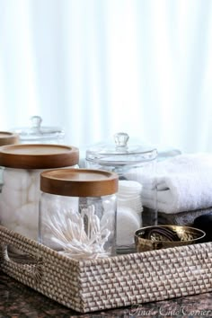 three jars with lids are sitting on a counter next to towels and other bathroom items