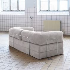 a couch sitting on top of a tiled floor in a room with white tile walls