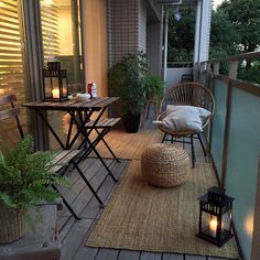 a porch with chairs, table and lanterns on the deck at night or in front of an apartment building