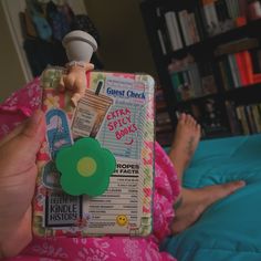 a person laying on a bed with a book in their hand and an object sticking out of the cover