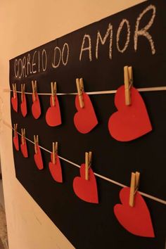 there is a black board with red hearts on it and clothes pins attached to the strings