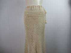 "Vintage 1970s hippy crochet skirt. Made of antique white cotton. Bohemian hippy style. Floor length with a drawstring waist. Crocheted on the bias so it is form fitting. Slight fish tail at bottom. No label. About a size medium. Actual measurements are: 32\"(adjusts bigger with drawstring) around the waist 38\" (stretches to 42\") around the hips 40\" overall length In very good condition." Bohemian Crochet Lace Bottoms For Festival, Beige Crochet Skirt For Summer, Summer Crochet Skirt In Beige, Summer Beige Crochet Skirt, Bohemian Skirt With Crochet Trim For Spring, Bohemian Spring Skirt With Crochet Trim, Beach Cotton Skirt With Crochet Trim, Spring Bohemian Skirt With Crochet Trim, Bohemian Crochet Festival Skirt