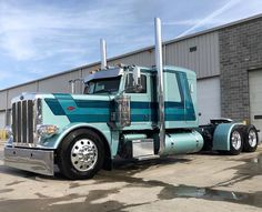 a blue semi truck parked in front of a building