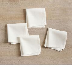 four white napkins sitting on top of a wooden table