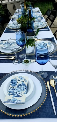 the table is set with blue and white plates, silverware, and napkins