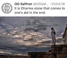 a man standing on top of a stone wall with clouds in the sky behind him