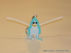 a crocheted penguin keychain hanging from a hook on a yellow surface