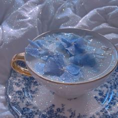 a blue and white cup filled with flowers on top of a saucer next to a cloth