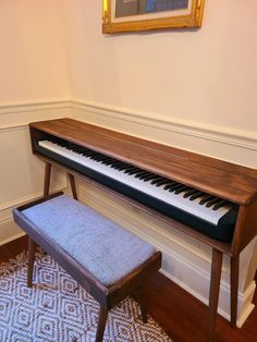 a piano sitting on top of a hard wood floor next to a bench with a footstool