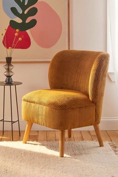 a yellow chair sitting on top of a wooden floor next to a vase filled with flowers