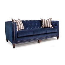 a blue velvet couch with striped pillows on it's arms and backrests