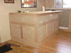 a wooden counter in the middle of a room with hard wood flooring next to it