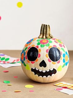 a painted pumpkin with a skull on it and confetti sprinkles