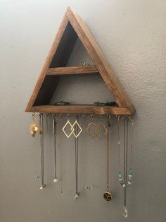 a triangle shaped wooden shelf with jewelry hanging from it