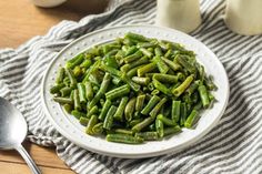 a white plate topped with green beans on top of a table