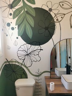 a bathroom decorated with flowers and leaves painted on the wall, along with a toilet