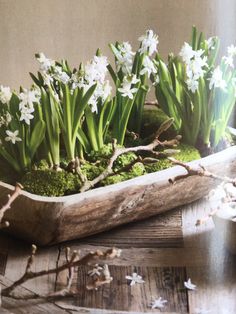 a wooden tray filled with white flowers on top of a table