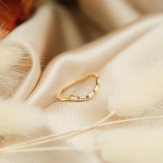 a gold ring sitting on top of a white cloth next to feathery material and feathers