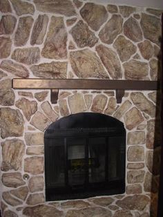 a stone fireplace with a mantle and shelf above it