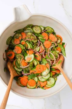 a white bowl filled with cucumbers, carrots and onions