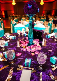 the table is set with purple and blue linens, silverware, and napkins