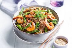 a bowl filled with noodles and shrimp next to chopsticks