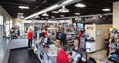 people are shopping in a store with many items on the shelves and around them is a cash register