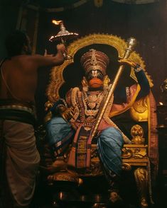 a man sitting on top of a golden throne next to another man holding a lamp