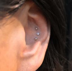 a woman's ear with three small diamond studs