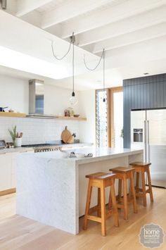 a kitchen with two stools in front of the counter and an island next to it