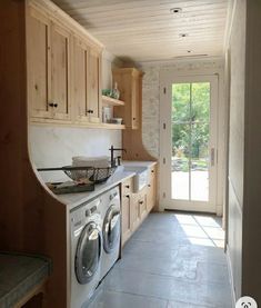 a washer and dryer in a small room with wooden cabinetry on the walls