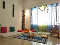 a living room filled with lots of furniture next to a window covered in sheer curtains