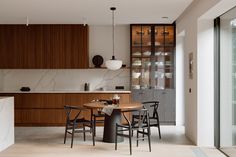 a modern kitchen and dining area with marble counter tops, wooden cabinets, and black chairs