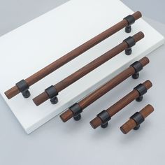 four pieces of wood and black handles on a white surface