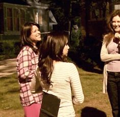 three women standing in the grass talking to each other