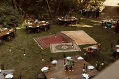 an overhead view of a table and rug in the middle of a grassy area surrounded by trees