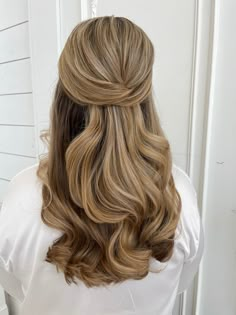 the back of a woman's head with long, wavy hair in half - up style