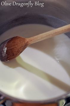 a wooden spoon in a pot filled with milk