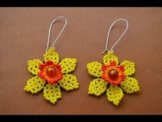 two pairs of yellow and red beaded earrings on a brown surface with beads attached to them