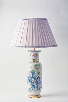 a lamp that is on top of a table with a purple shade over the lamp